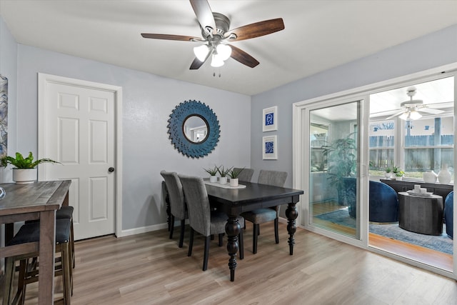 dining space featuring baseboards, a ceiling fan, and light wood finished floors