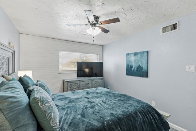 bedroom featuring ceiling fan, baseboards, visible vents, and a textured ceiling