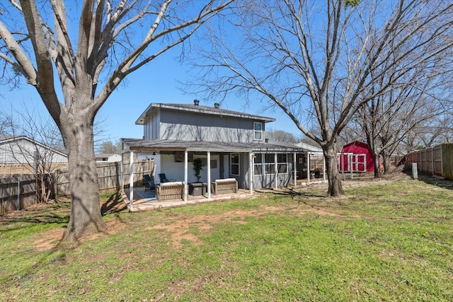 rear view of property with a storage unit, a lawn, a fenced backyard, an outdoor structure, and a sunroom