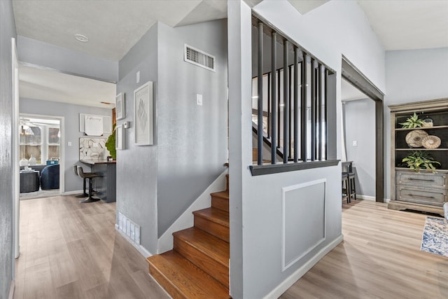 staircase with visible vents, baseboards, and wood finished floors