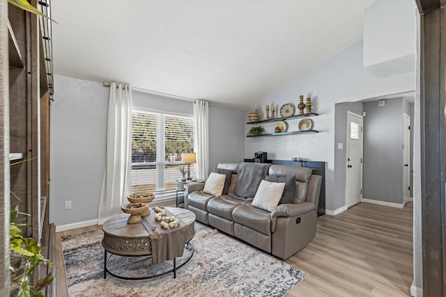 living room with baseboards, lofted ceiling, and light wood finished floors