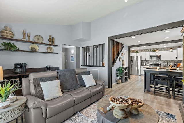 living room with stairway, lofted ceiling, and light wood-style floors