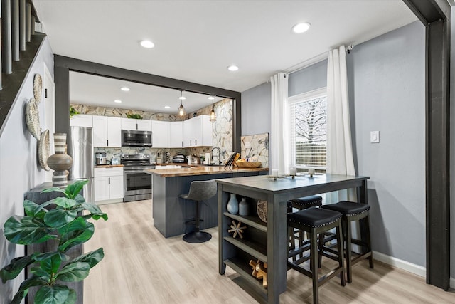 kitchen with backsplash, light wood-style flooring, white cabinets, stainless steel appliances, and wood counters