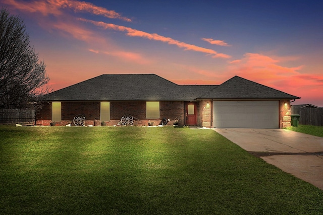 single story home featuring driveway, a garage, roof with shingles, a front yard, and brick siding