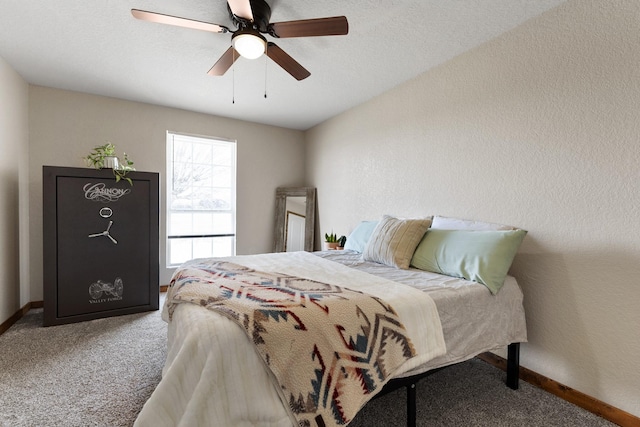 carpeted bedroom featuring a textured wall, ceiling fan, and baseboards