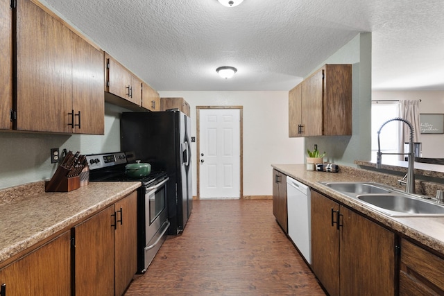 kitchen featuring a textured ceiling, dark wood-style flooring, a sink, dishwasher, and stainless steel range with electric stovetop