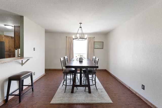 dining room with dark wood finished floors, a textured wall, an inviting chandelier, a textured ceiling, and baseboards