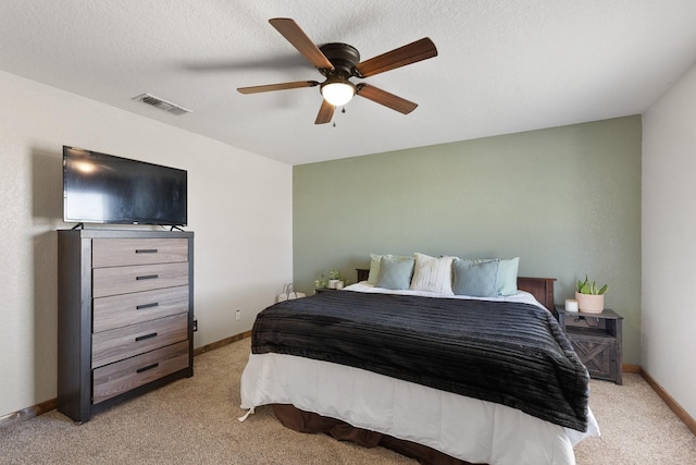 bedroom featuring visible vents, light carpet, baseboards, and a textured ceiling