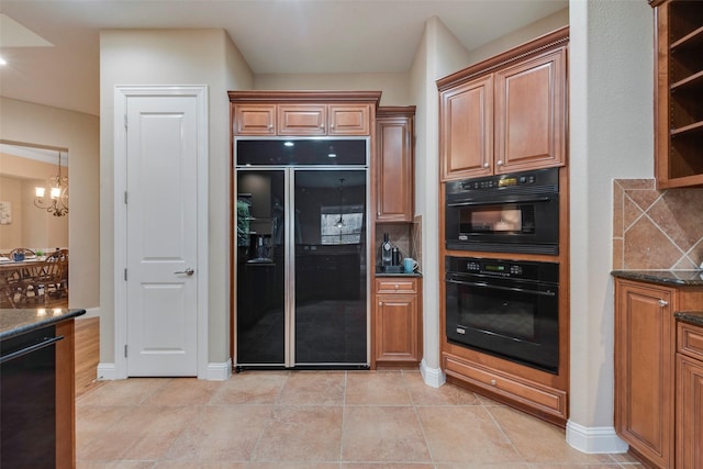 kitchen with dark stone counters, black appliances, a chandelier, open shelves, and backsplash