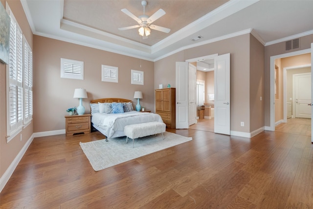 bedroom with ornamental molding, a tray ceiling, wood finished floors, and baseboards