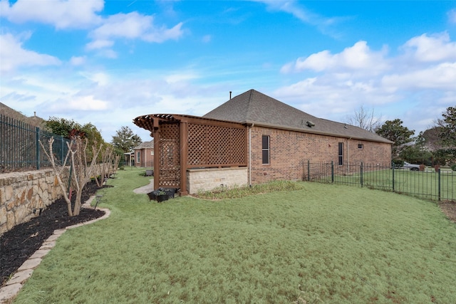 view of property exterior featuring roof with shingles, brick siding, a lawn, and a fenced backyard