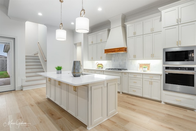 kitchen featuring tasteful backsplash, light wood-style floors, premium range hood, and stainless steel appliances