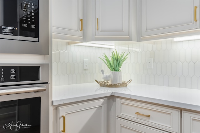 room details featuring light countertops, appliances with stainless steel finishes, white cabinetry, and tasteful backsplash