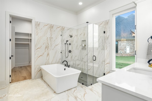 full bathroom featuring a spacious closet, a soaking tub, a marble finish shower, and vanity