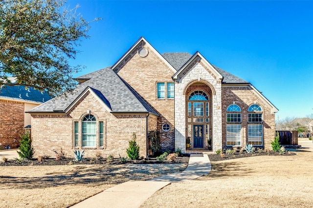 french country home with brick siding and roof with shingles