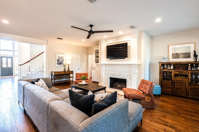 living area featuring visible vents, dark wood-type flooring, a high end fireplace, and stairway