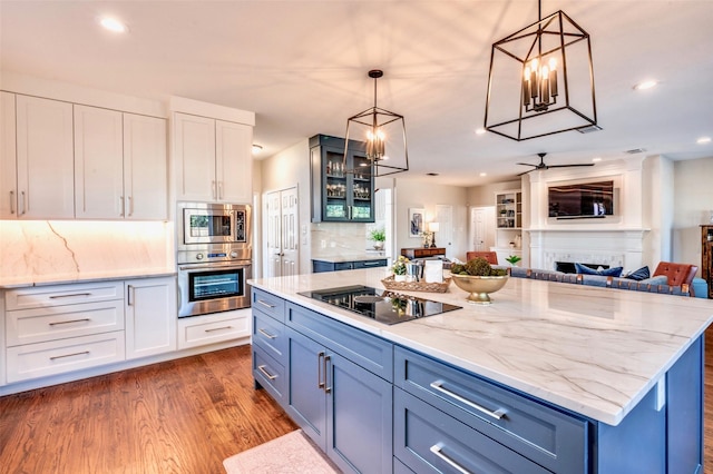 kitchen with a fireplace, dark wood-type flooring, white cabinetry, black electric stovetop, and a center island