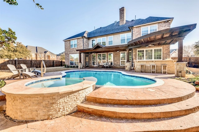 view of swimming pool with outdoor dry bar, a pool with connected hot tub, a pergola, a patio, and fence