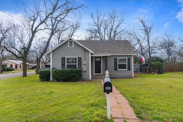 bungalow-style home featuring a front yard, roof with shingles, and fence