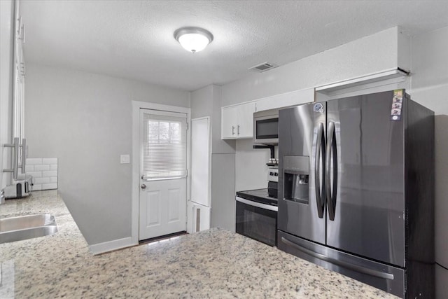 kitchen featuring stainless steel appliances, visible vents, decorative backsplash, white cabinets, and a sink