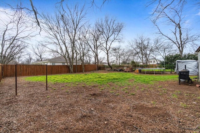 view of yard with a trampoline and fence