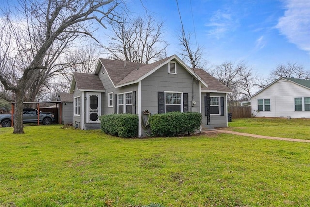 bungalow with roof with shingles, a front yard, and fence