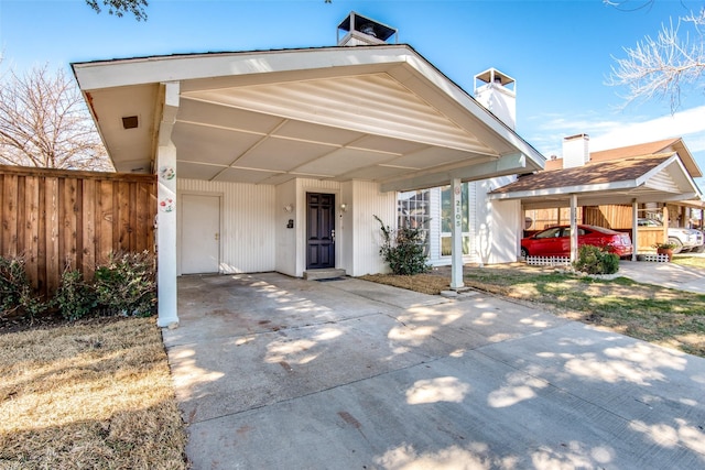 view of front facade featuring driveway, an attached carport, and fence