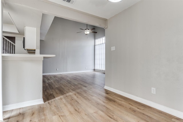 empty room featuring visible vents, baseboards, ceiling fan, a high ceiling, and light wood-style floors