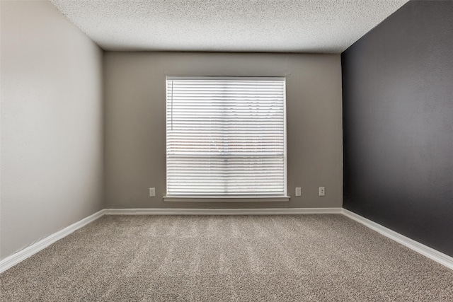 unfurnished room featuring a textured ceiling, baseboards, a wealth of natural light, and carpet flooring