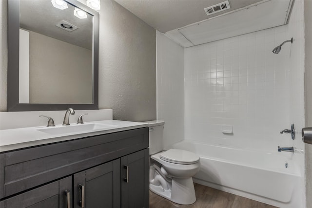 full bath with visible vents, a textured wall, toilet, wood finished floors, and vanity