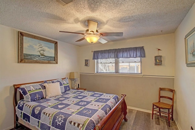 bedroom with visible vents, baseboards, ceiling fan, wood finished floors, and a textured ceiling