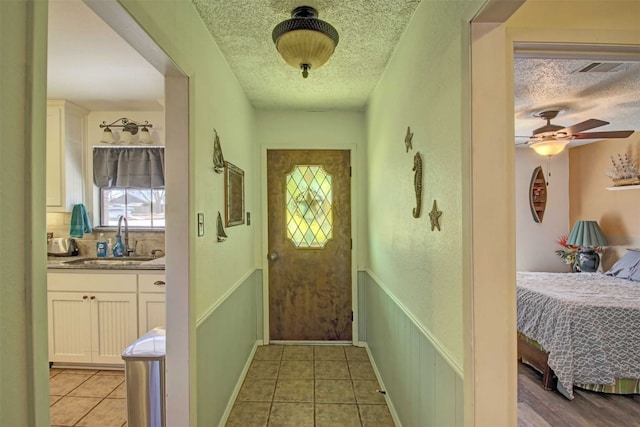 entryway with light tile patterned flooring, a textured ceiling, and a sink