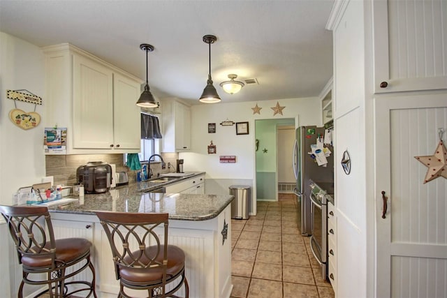 kitchen featuring visible vents, stainless steel electric stove, light tile patterned floors, a peninsula, and a sink