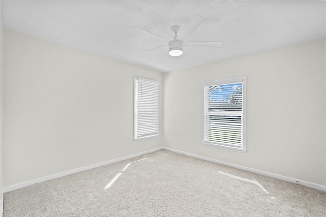 spare room with light colored carpet, ceiling fan, and baseboards