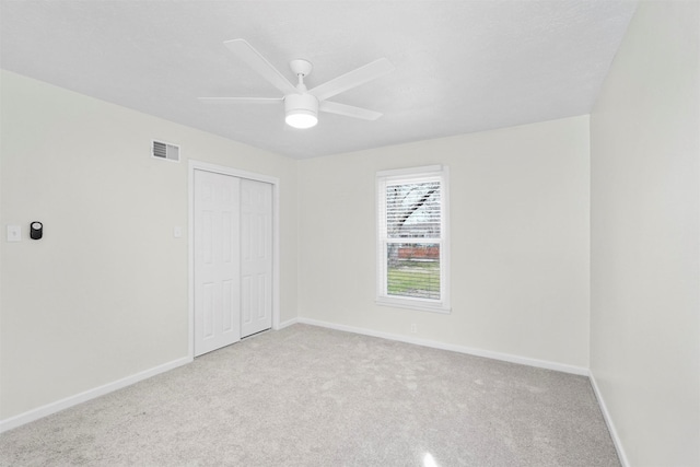 unfurnished bedroom featuring a closet, visible vents, a ceiling fan, carpet flooring, and baseboards