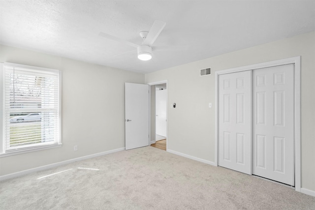 unfurnished bedroom with ceiling fan, carpet floors, visible vents, baseboards, and a closet