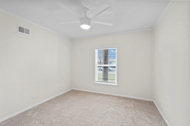 carpeted empty room with visible vents, baseboards, ceiling fan, ornamental molding, and a textured ceiling