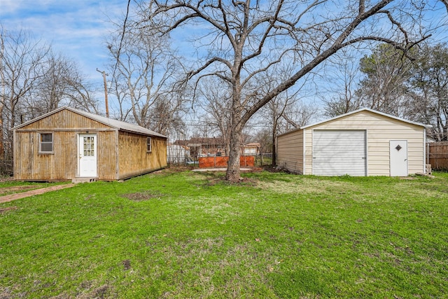 view of yard featuring driveway, an outdoor structure, fence, and a detached garage