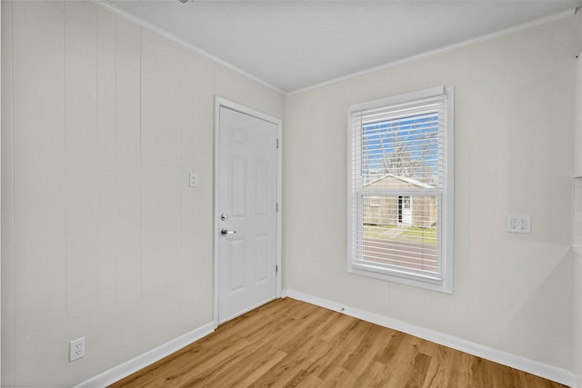 empty room with baseboards, light wood finished floors, and crown molding