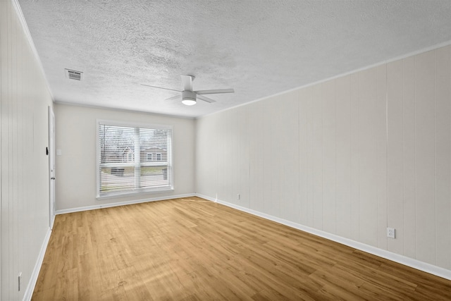 empty room featuring baseboards, visible vents, a ceiling fan, wood finished floors, and a textured ceiling