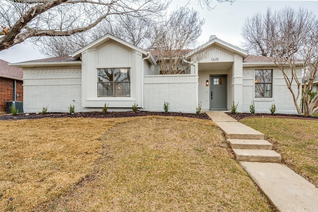 view of front of property featuring cooling unit, brick siding, and a front lawn