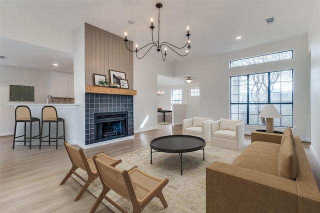 living room with light wood-style floors, a fireplace, visible vents, and recessed lighting