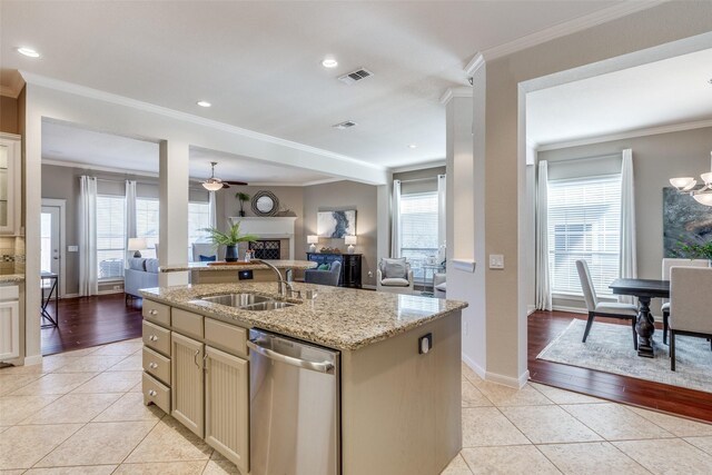 kitchen featuring light tile patterned floors, a fireplace, a sink, stainless steel dishwasher, and open floor plan