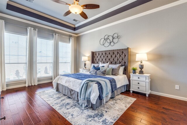 bedroom with visible vents, ornamental molding, hardwood / wood-style flooring, baseboards, and a raised ceiling