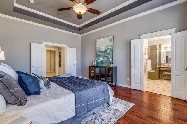 bedroom featuring visible vents, crown molding, baseboards, a raised ceiling, and wood-type flooring