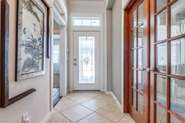 foyer entrance with light tile patterned floors, a textured wall, baseboards, and ornamental molding