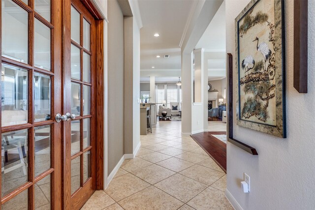 corridor featuring light tile patterned floors, baseboards, recessed lighting, french doors, and crown molding