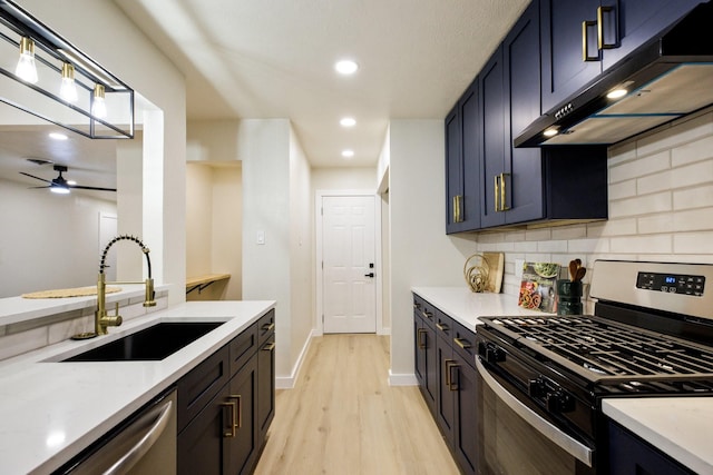 kitchen featuring light countertops, backsplash, appliances with stainless steel finishes, a sink, and under cabinet range hood