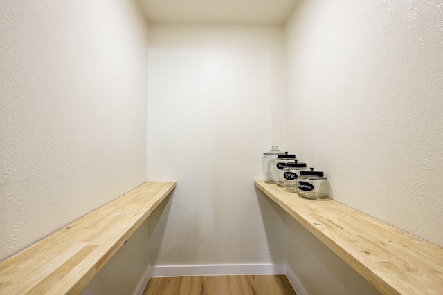 spacious closet with light wood finished floors and built in desk