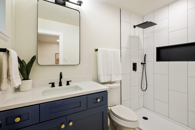 bathroom with a tile shower, vanity, and toilet